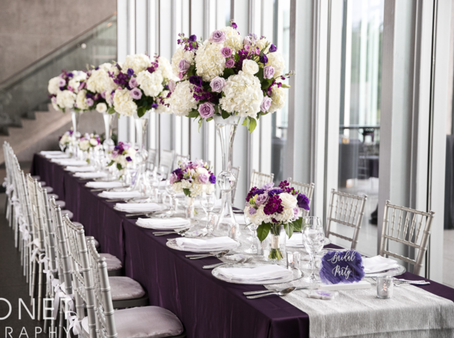 Purple and white wedding reception table with tall floral arrangements