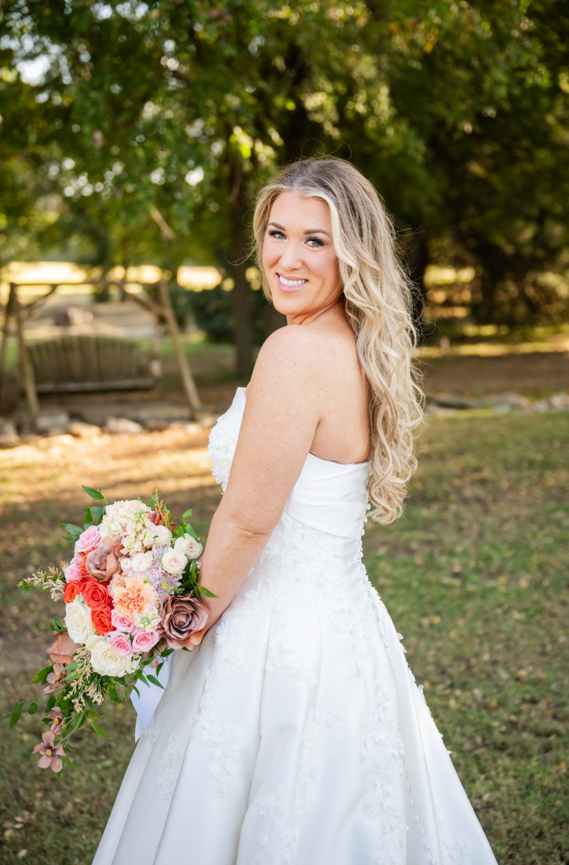 Bride smiling outdoors with a colorful bouquet