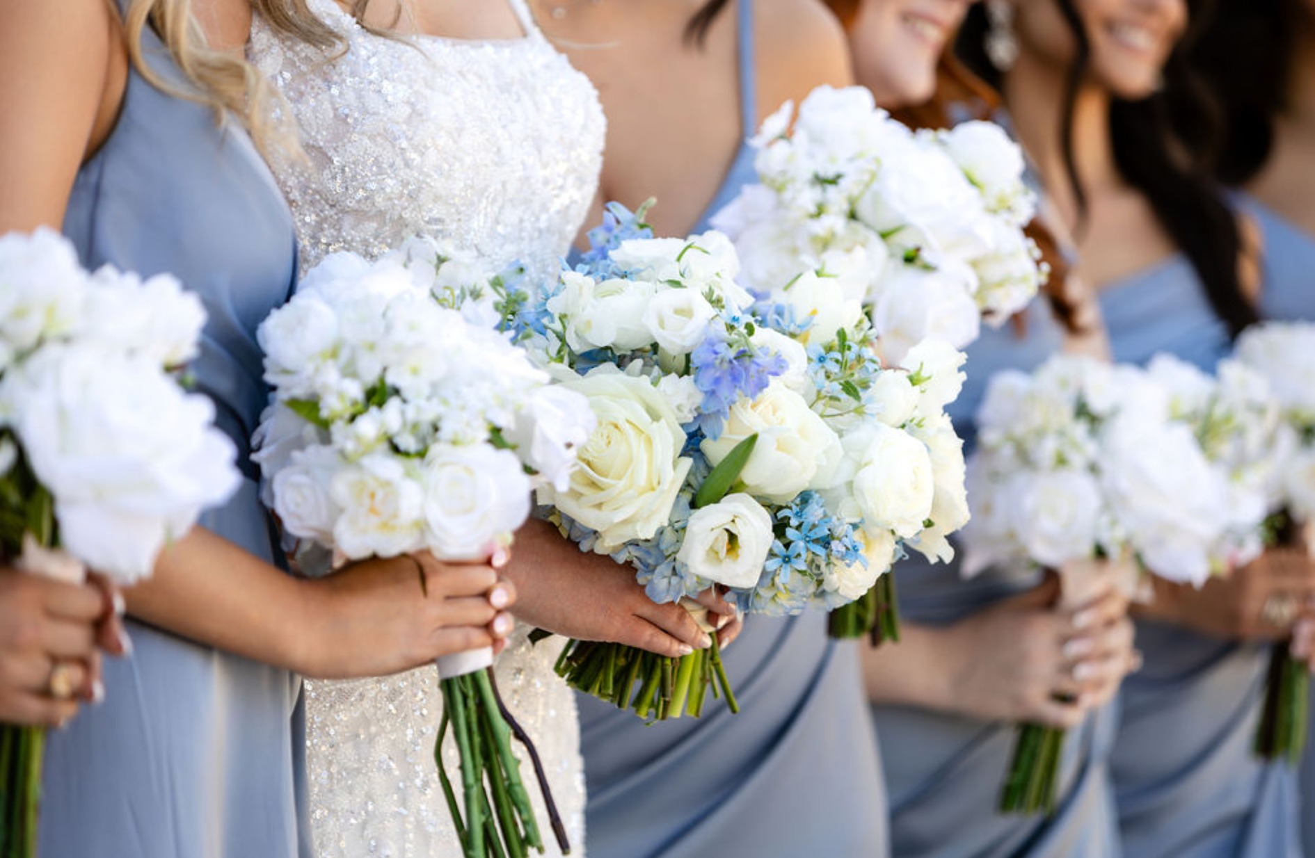 Bride and bridesmaids holding white and blue bouquets