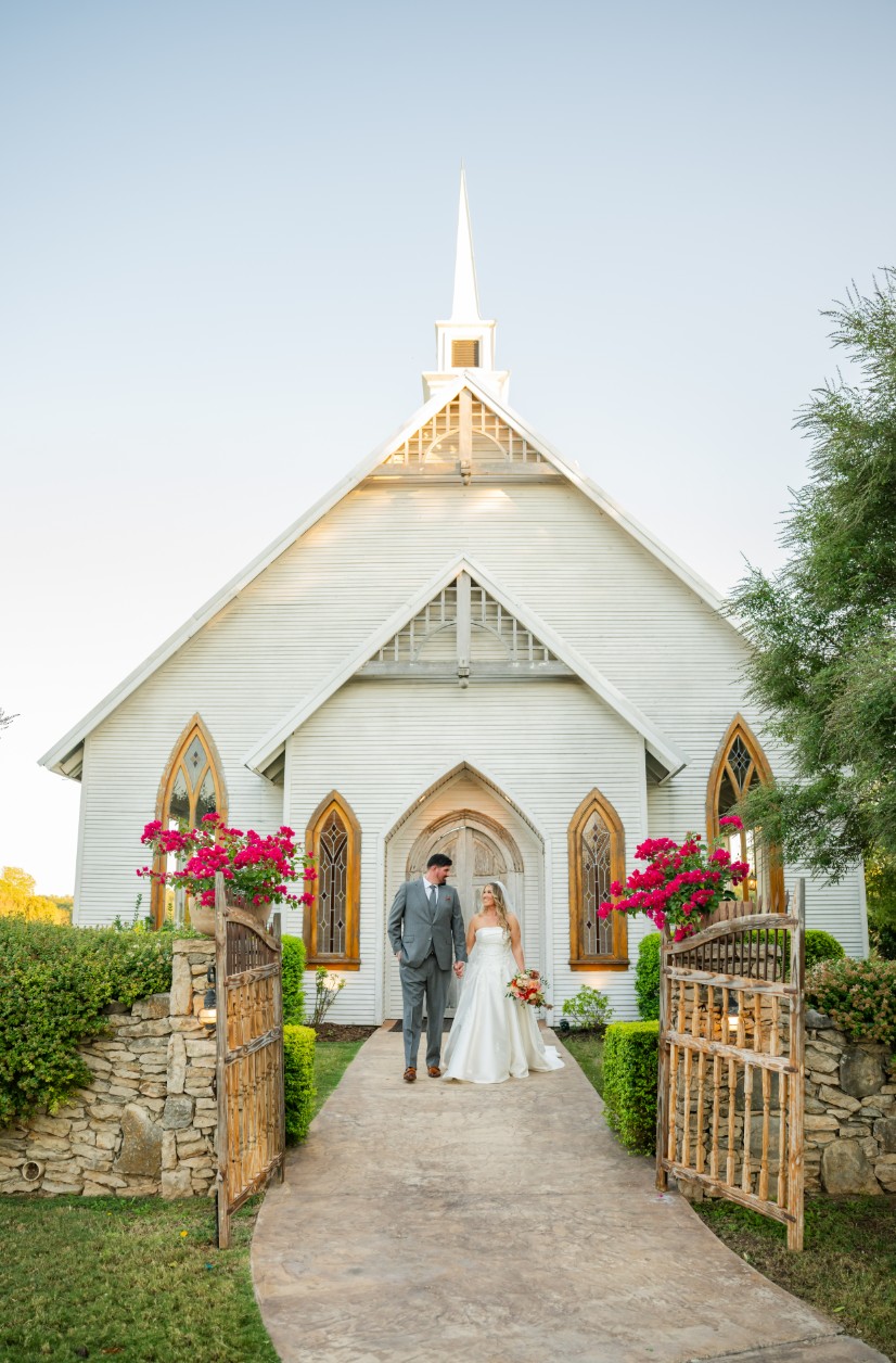 Couple standing at a chapel entrance with bright florals