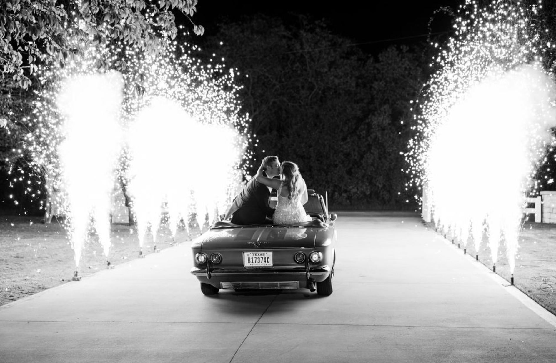 Newlyweds kissing in a getaway car during a sparkler sendoff
