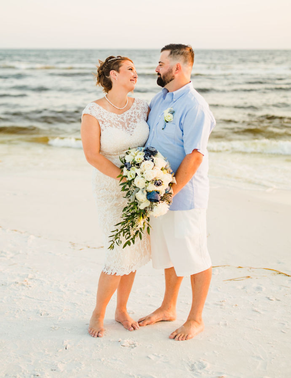 Couple on beach wedding day with bouquet