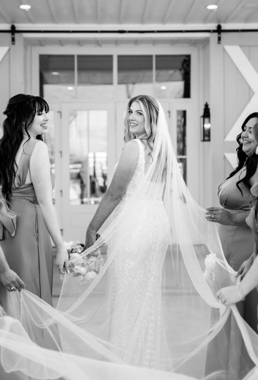 Bride with bridesmaids holding her veil