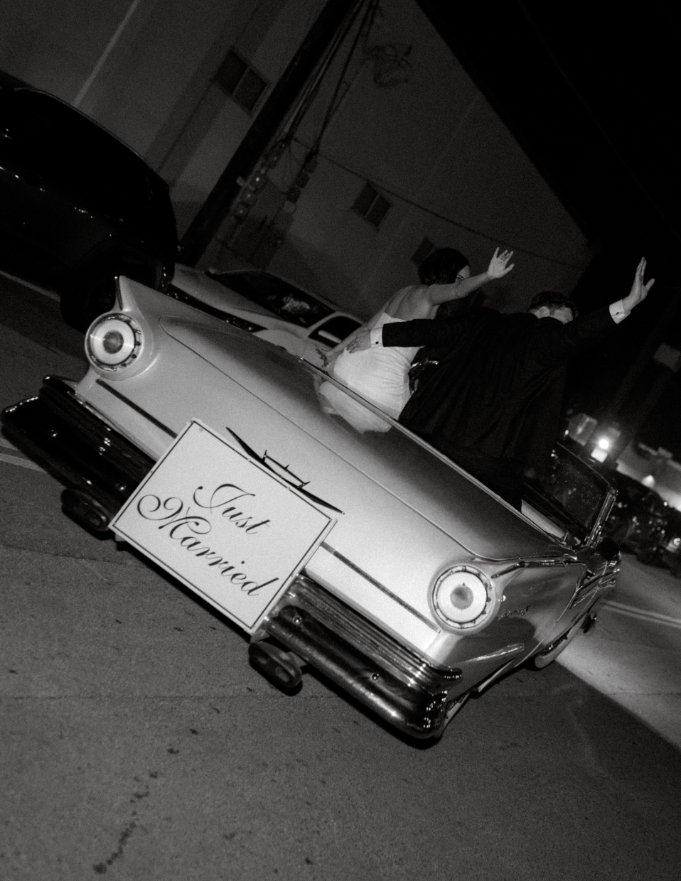 Newlyweds leaving in a vintage getaway car