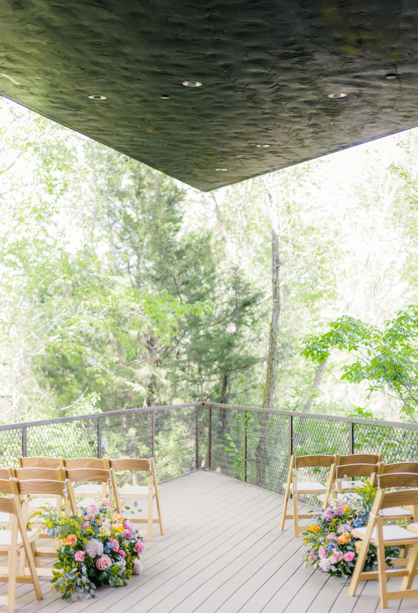 Outdoor ceremony setup with floral arrangements and wooden chairs
